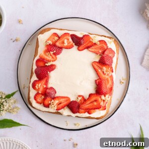 A square elderflower cake topped with strawberries