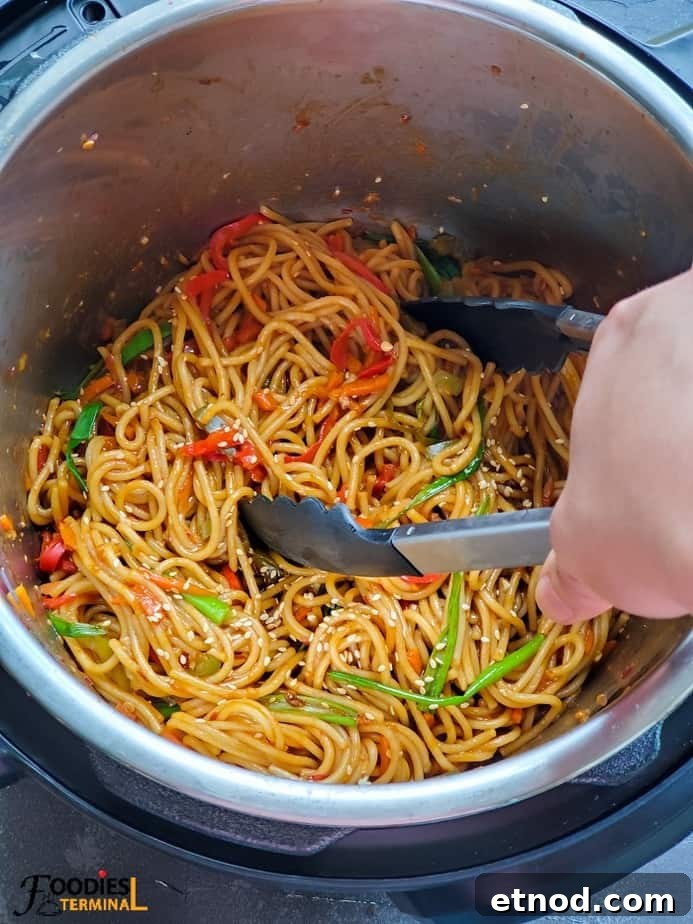 chili garlic noodles in instant pot with a noodle tong