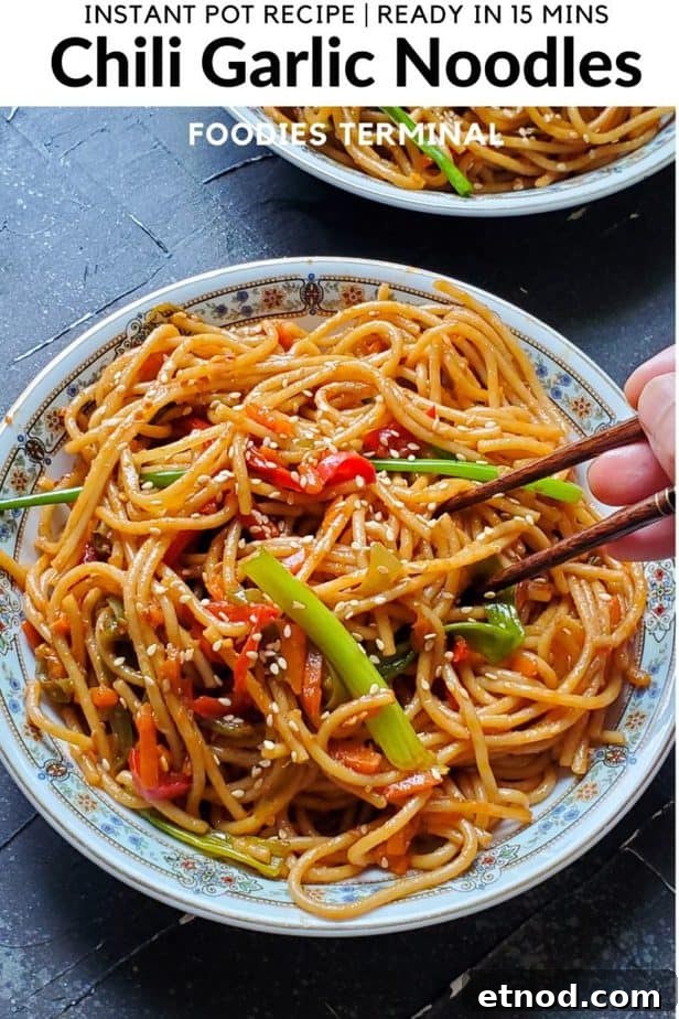 Instant pot chili garlic noodles with chopsticks tucked in served in a white plate