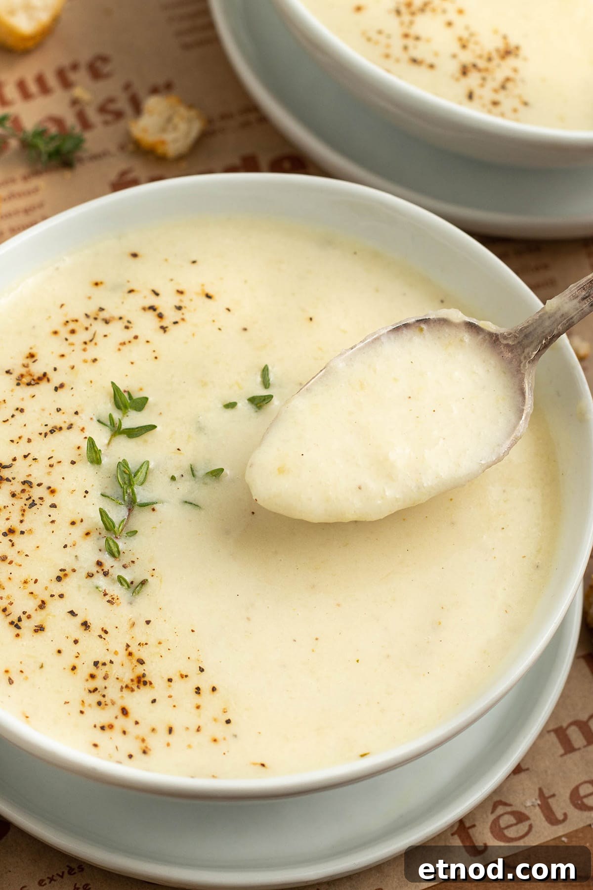 Cream of Onion Soup Recipe: Rich, Silky Classic Soup 3 A spoonful of cream of onion soup being lifted out of a white bowl of soup.