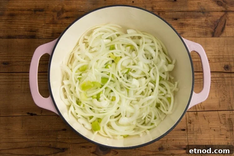 Cream of Onion Soup Recipe: Rich, Silky Classic Soup 6 Sliced onions and chopped celery in a large pot on a wooden tabletop.