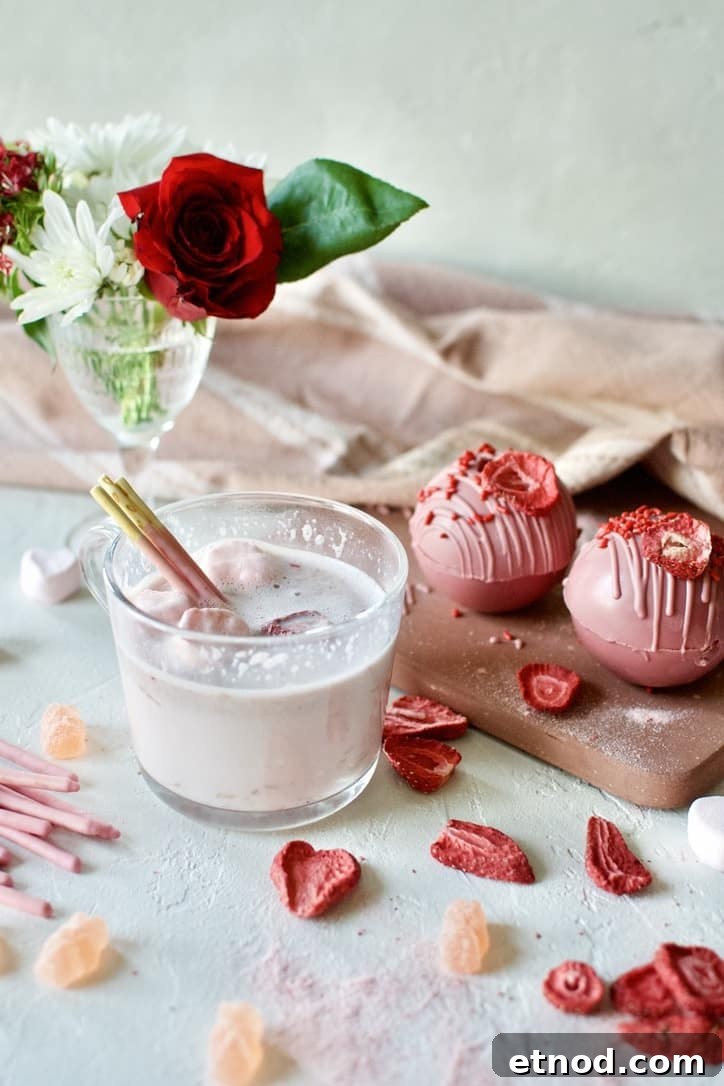 Pink Hot Chocolate in a mug with heart shaped marshmallows after using a Pink Hot Chocolate Bomb to to make the hot cocoa.