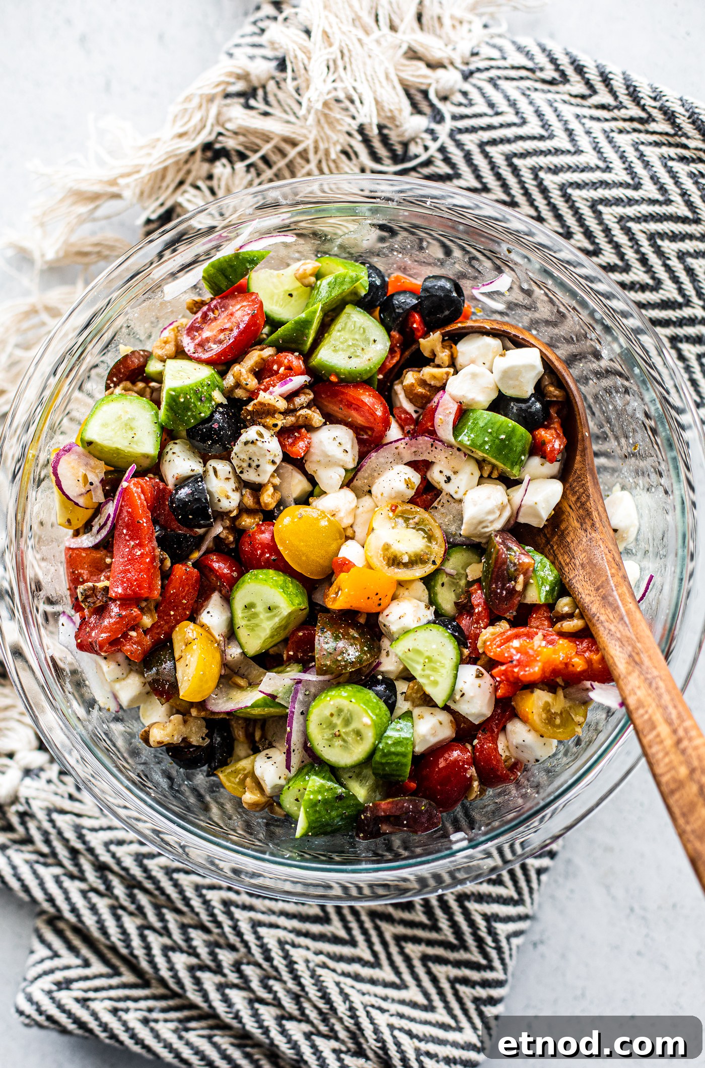 Crisp Greek Cucumber and Tomato Salad Recipe 4 Glass serving bowl full of Greek cucumber salad with a wooden serving spoon in the bowl.