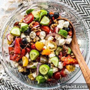 Crisp Greek Cucumber and Tomato Salad Recipe 6 Glass serving bowl full of Greek cucumber salad with a wooden serving spoon in the bowl.