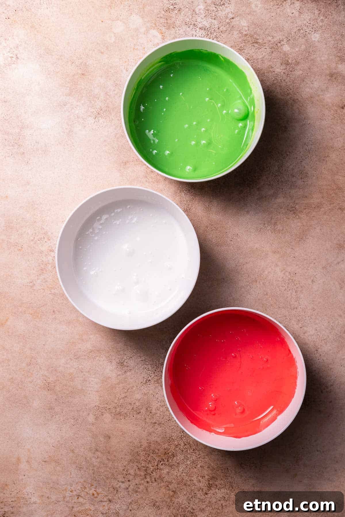 Chewy Christmas Sugar Cookie Bars with Festive Sprinkles 8 Three bowls of royal icing colored red, white, and green.