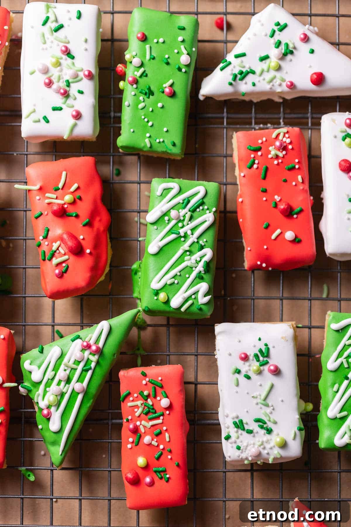 Chewy Christmas Sugar Cookie Bars with Festive Sprinkles 9 Decorated sugar cookie bars covered in frosting and sprinkles on a wire rack.