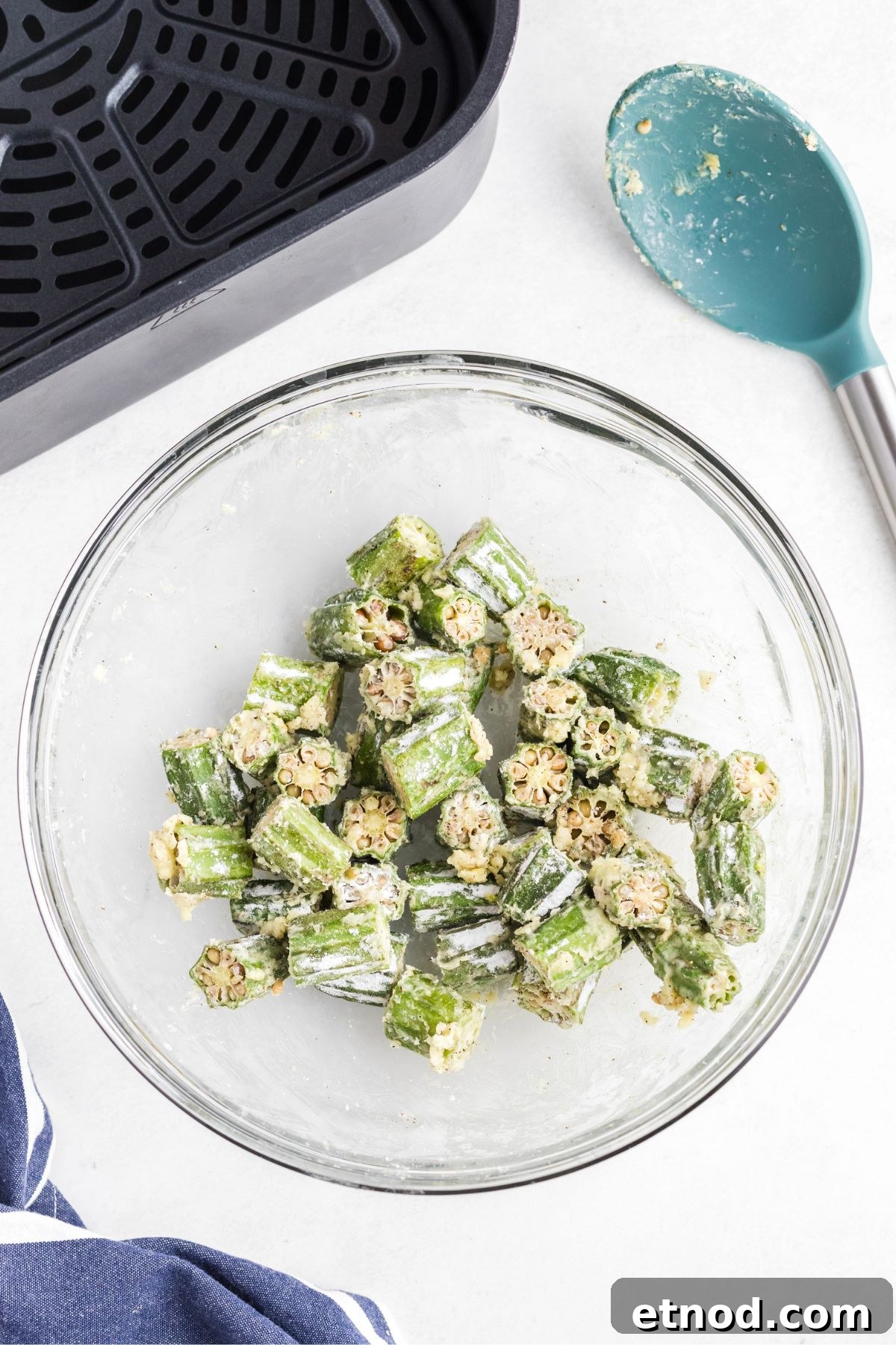 Crispy Air-Fried Okra Recipe for Perfectly Tender Bites 5 Fresh okra cut into pieces, tossed in a clear glass bowl with cornstarch, garlic, and seasonings.