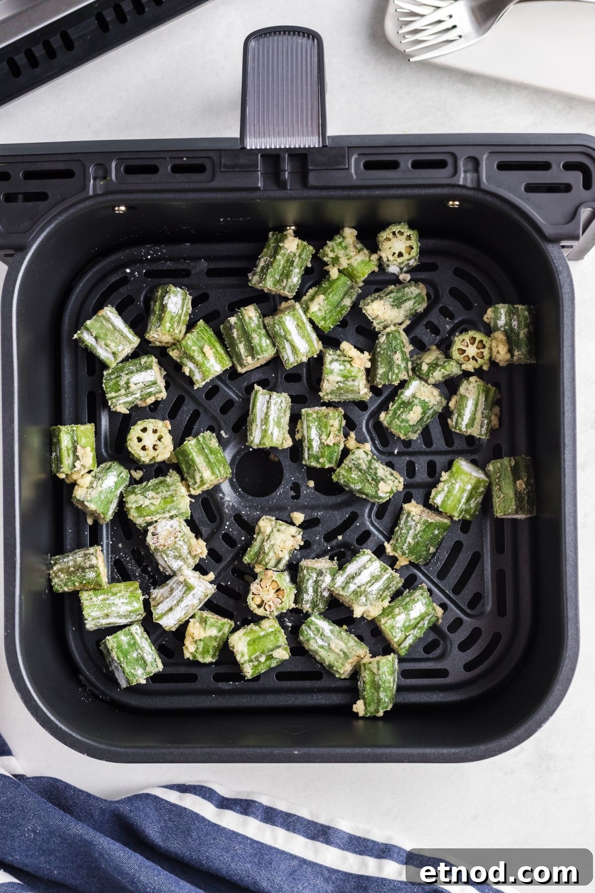 Crispy Air-Fried Okra Recipe for Perfectly Tender Bites 6 Coated okra pieces in an air fryer basket before being cooked.