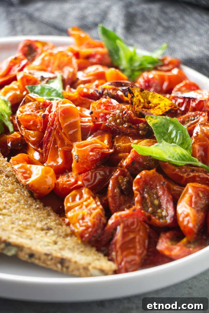 Crispy Air Fryer Cherry Tomatoes Recipe in Minutes 9 Air fryer cherry tomatoes on a plate with basil garnish.