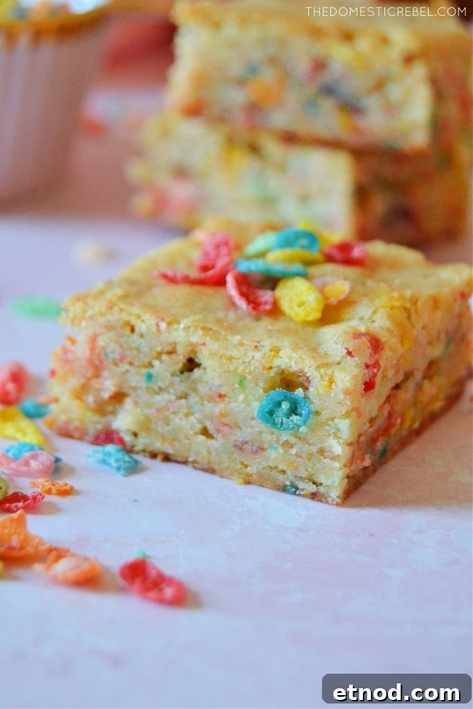 A piece of a fruity pebble blondie on a pink board
