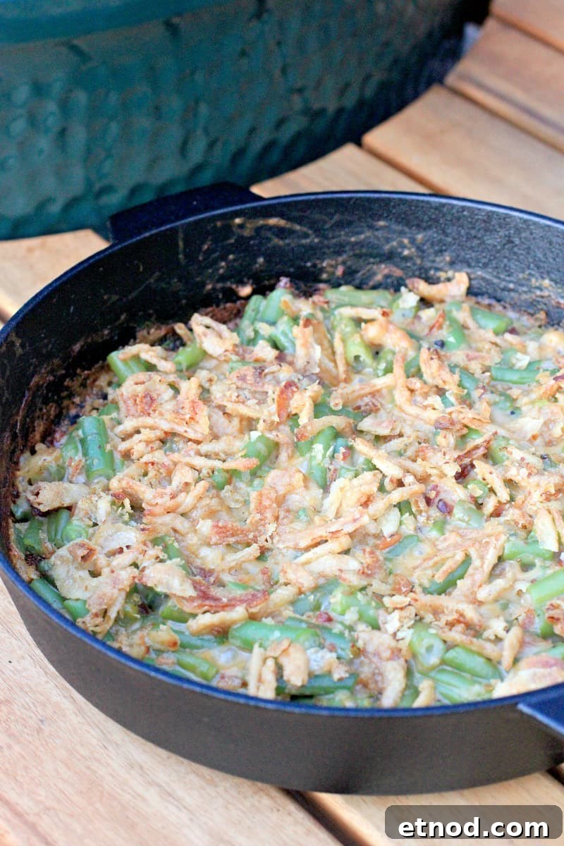 Smoky Grilled Green Bean Casserole with Crispy Bacon 8 cooked green bean casserole in cast iron skillet on table next to big green egg