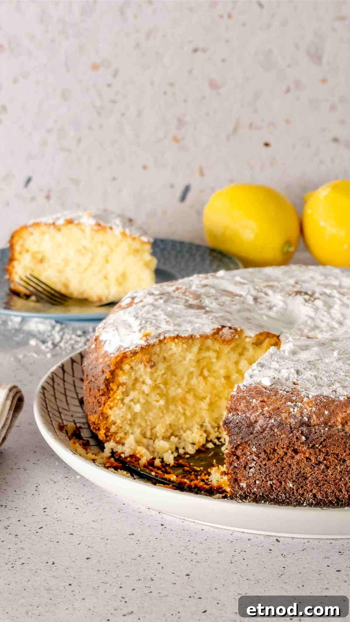 Zesty Lemon Yogurt Cake Recipe with Moist, Tangy Crumb 2 A lemon and yogurt cake with a slice cut out of it and placed in the background.