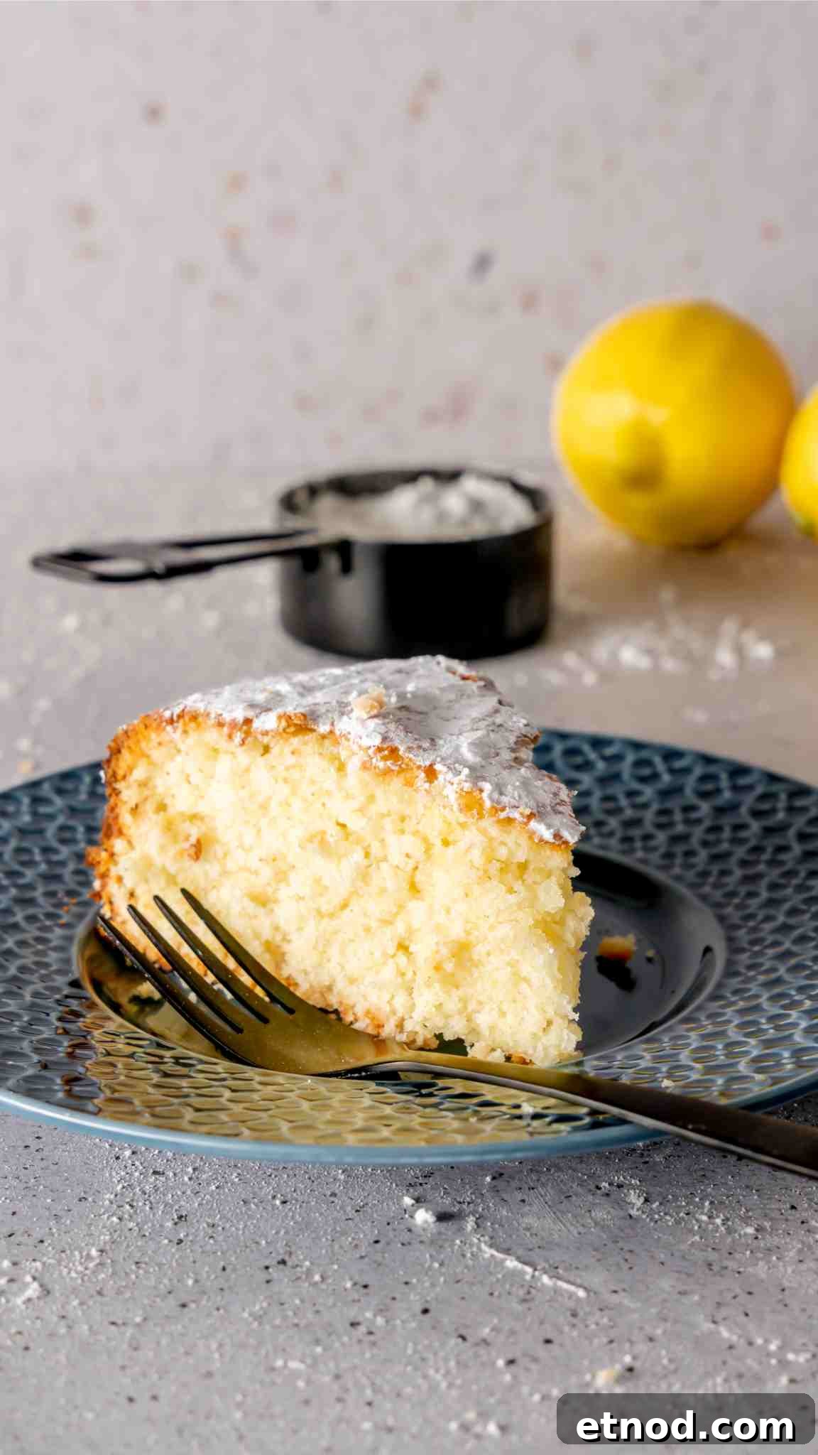 Zesty Lemon Yogurt Cake Recipe with Moist, Tangy Crumb 3 A slice of lemon and yogurt cake on a blue ceramic plate with a black fork.