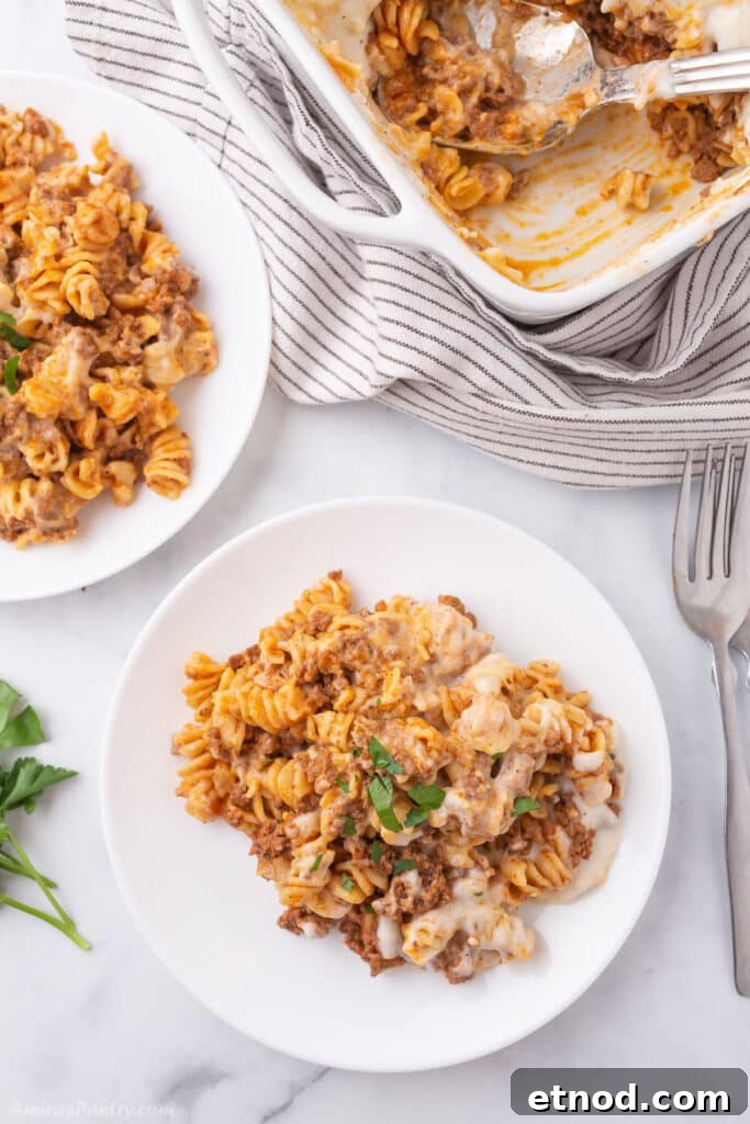 Two white plates with pasta and a baking dish next to them.
