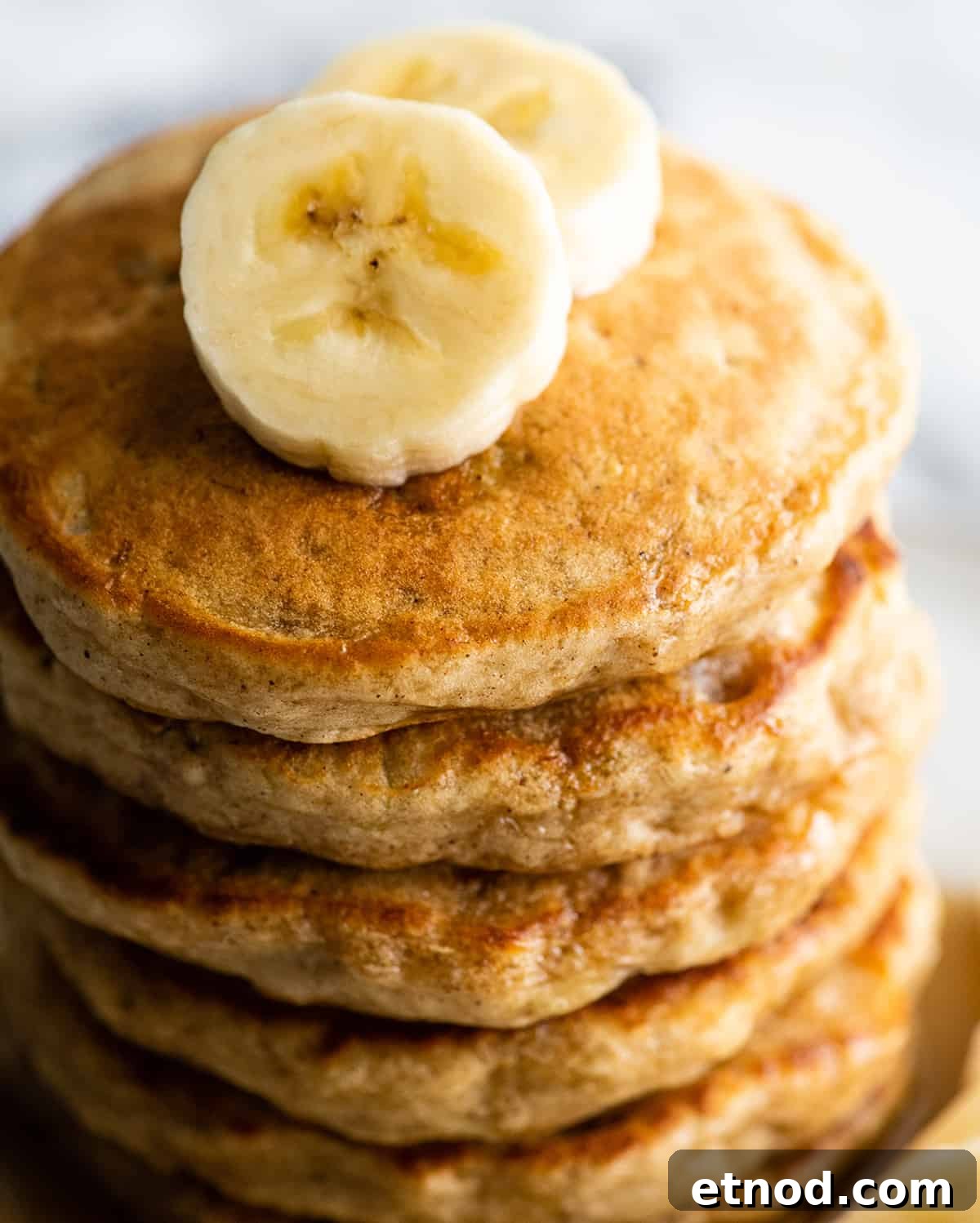 Fluffy Banana Pancake Recipe: Light, Tender Banana Pancakes 2 overhead view of a stack of 6 banana pancakes with sliced bananas