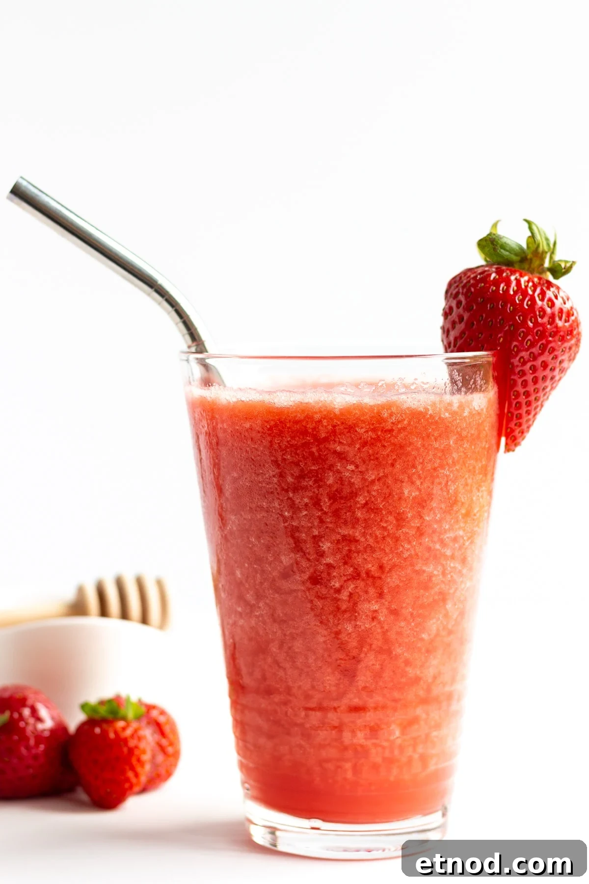 Refreshing Strawberry Slush Recipe for Summer Sips 2 Glass of strawberry slushie garnished with a strawberry and stainless steel straw.