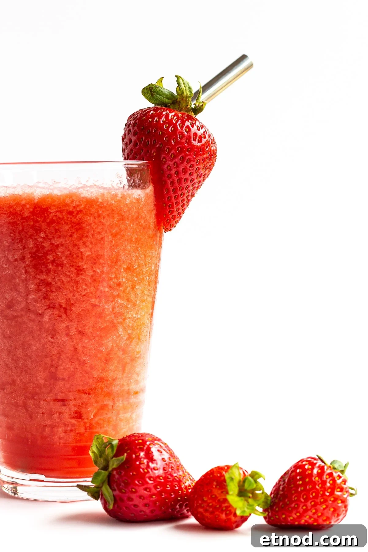 Refreshing Strawberry Slush Recipe for Summer Sips 6 Glass of strawberry slushie with fresh strawberries scattered next to it.