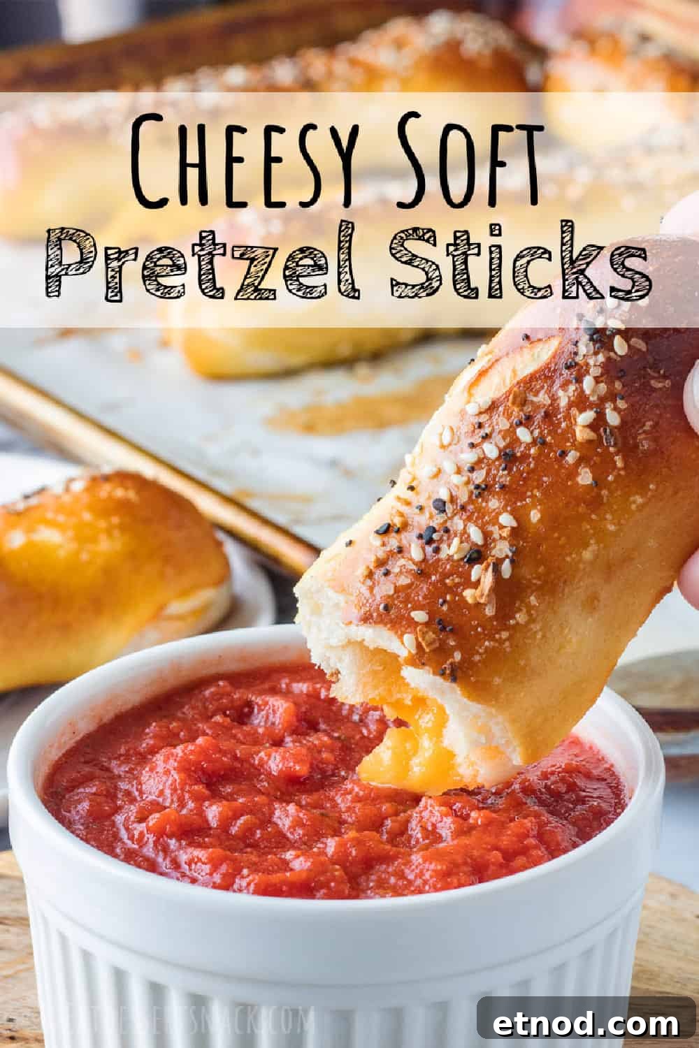 Easy cheese stuffed pretzel with homemade soft pretzel dough, stuffed with cheddar cheese and crunchy seasonings on top. Baked pretzel above white bowl of red sauce. Text overlay.