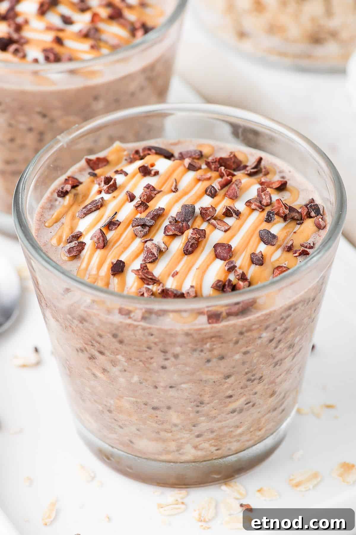 Jar of overnight oats, sitting on a white plate, garnished with peanut butter and cacao nibs.
