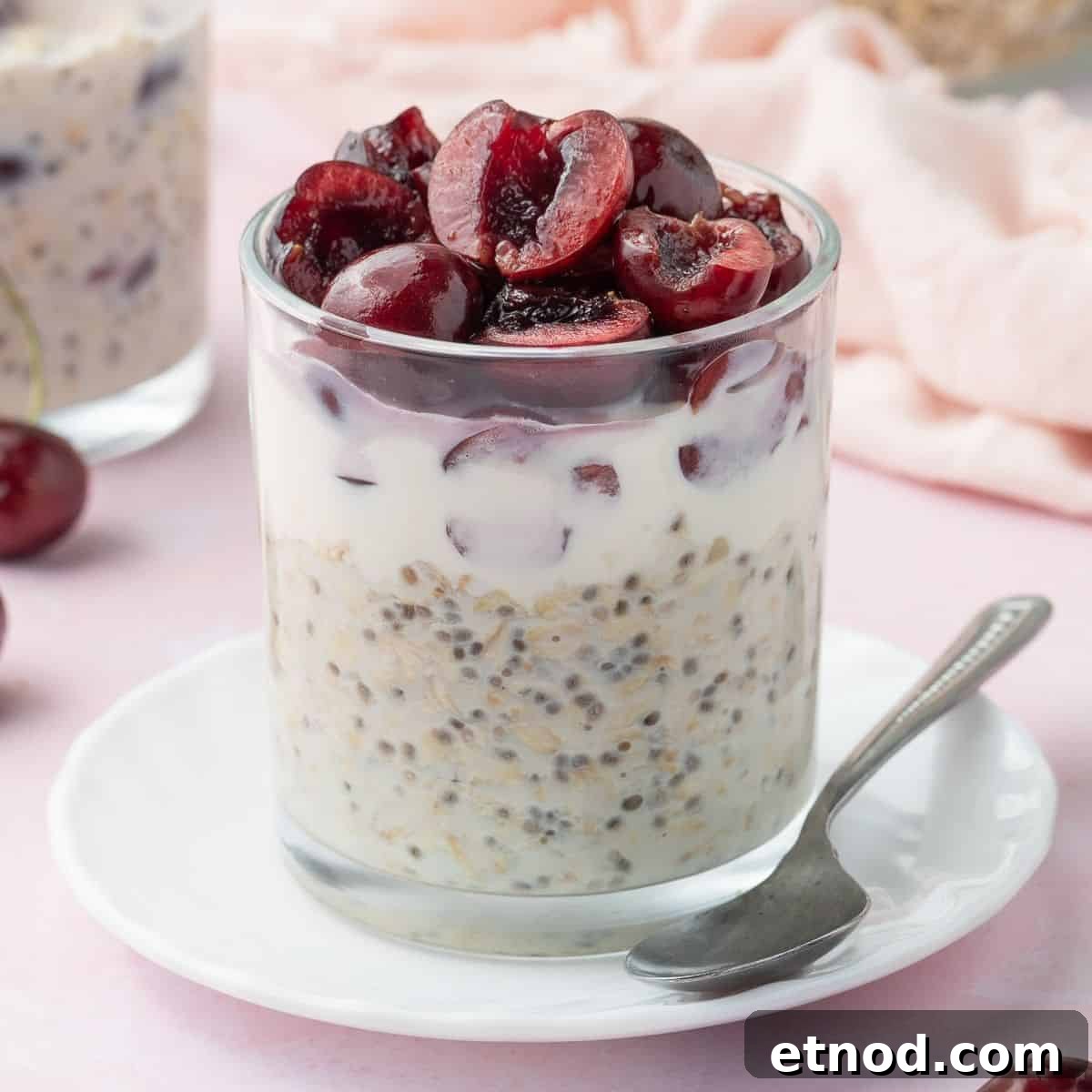 Glass jar of vanilla overnight oats, topped with halved cherries.