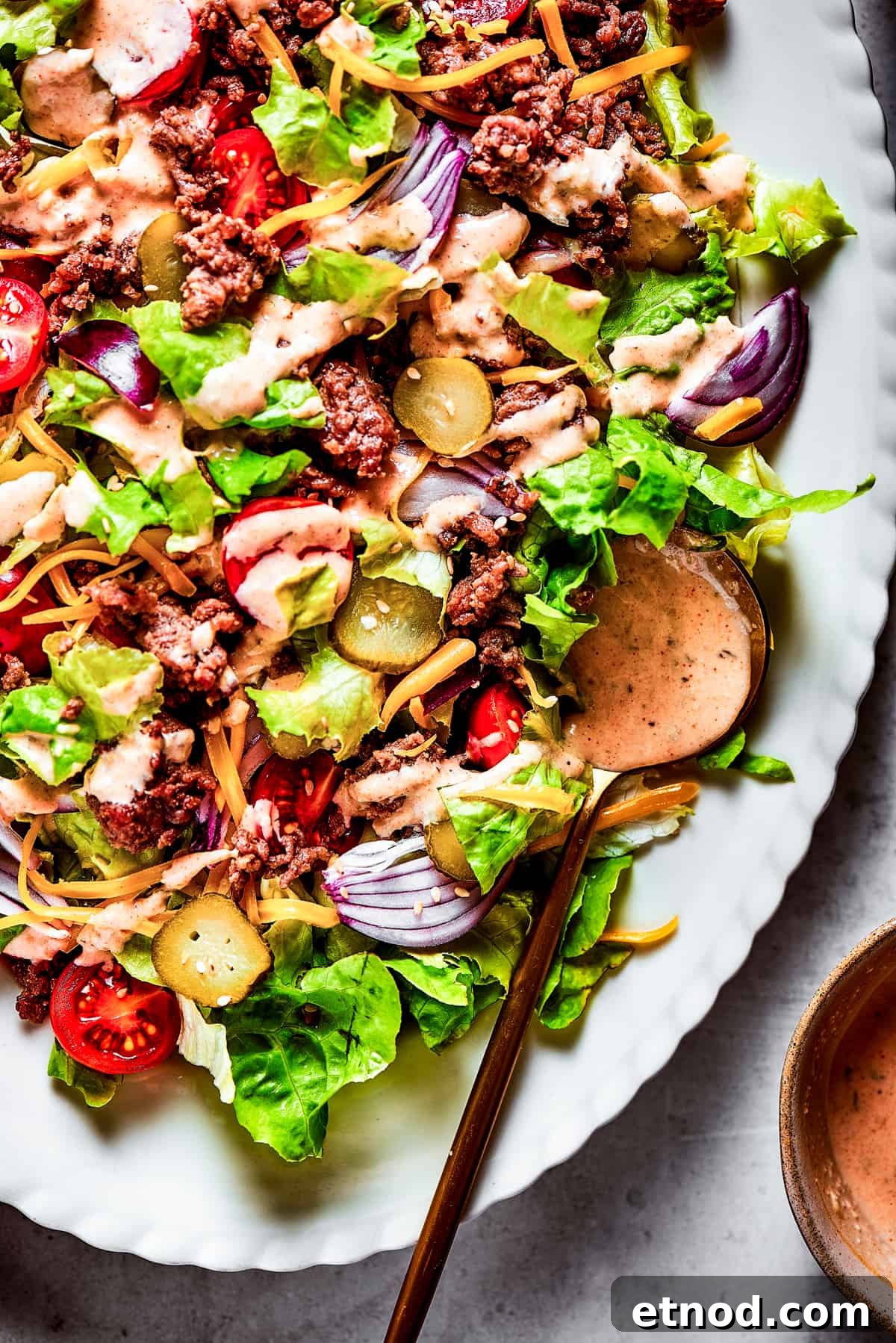 This Big Mac Salad brings all the classic flavors you love but with a healthier twist. It's a guilt-free way to satisfy your burger cravings. Close-up shot of Big Mac salad, showing the textures.