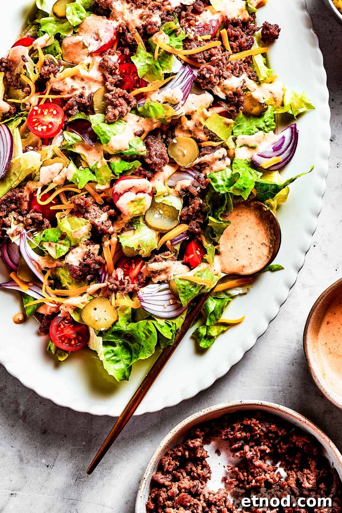 This Big Mac Salad brings all the classic flavors you love but with a healthier twist. It's a guilt-free way to satisfy your burger cravings. Close-up of a Big Mac Salad with red onion, ground beef, shredded cheese, and more.