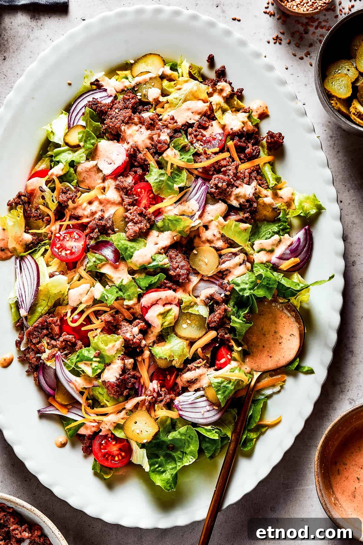 This Big Mac Salad brings all the classic flavors you love but with a healthier twist. It's a guilt-free way to satisfy your burger cravings. Overhead shot of a Big Mac salad on a white platter.