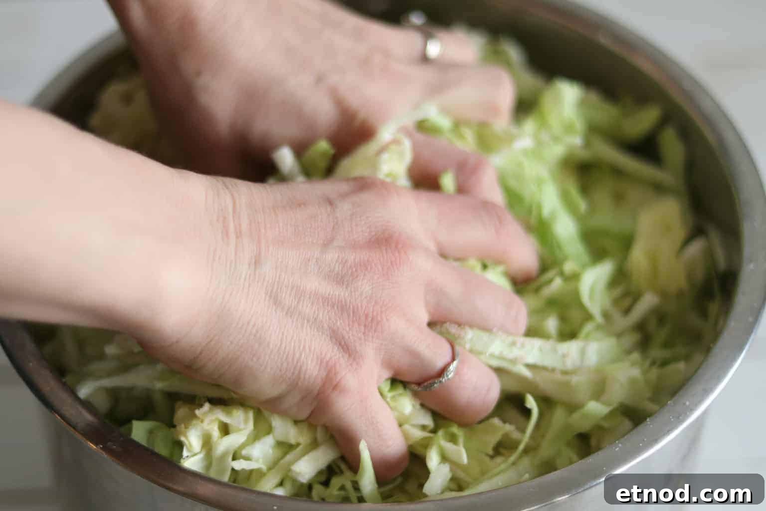 Quick 2-Ingredient Sauerkraut Recipe for Tangy Homemade Ferment 6 Hands mixing cabbage to make brine.