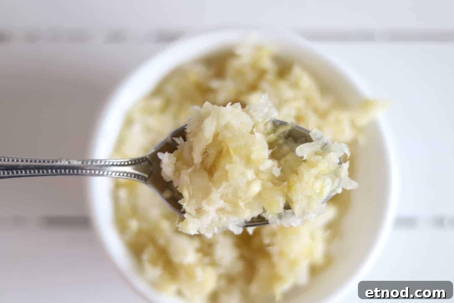 Quick 2-Ingredient Sauerkraut Recipe for Tangy Homemade Ferment 9 Spoon full of sauerkraut with bowl of sauerkraut in background.