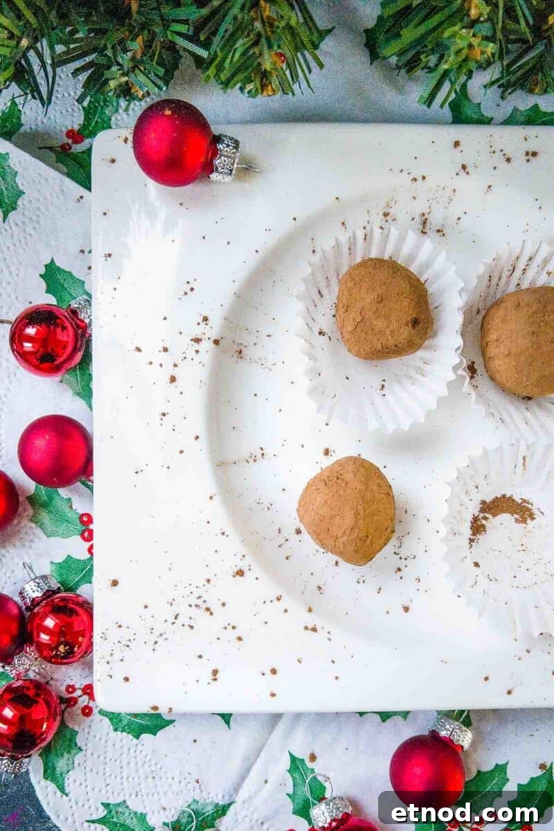 Biscoff Truffles Made Without Cream Cheese — Simple No-Bake Recipe 2 Scrumptious Biscoff truffles on white plate. Decorated with red Christmas baubles on the side.
