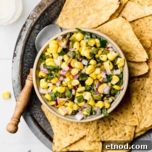 Chipotle roasted chili corn salsa in small bowl next to chips and spoon.