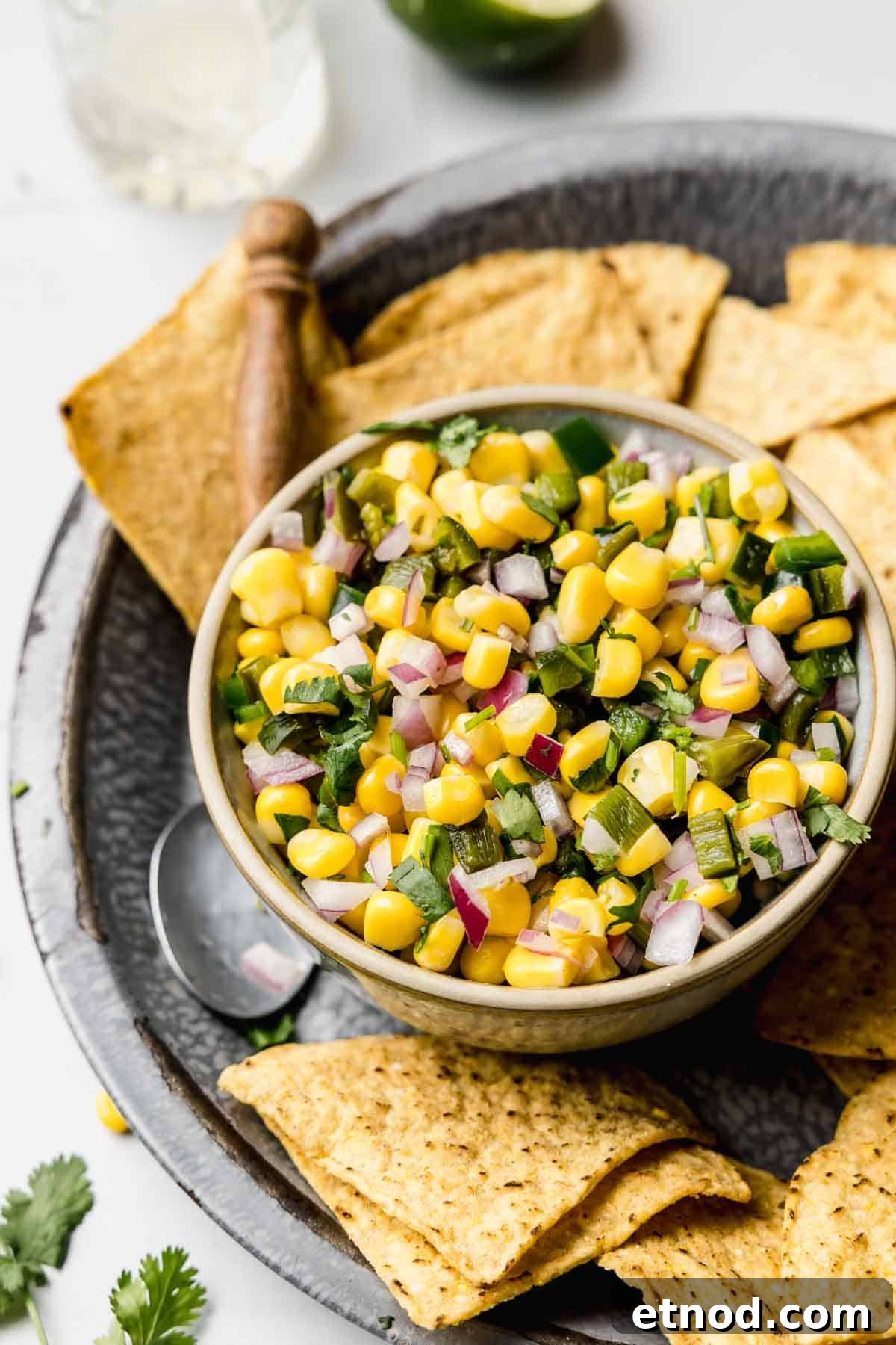 Sweet corn salsa in a small bowl next to tortilla chips.