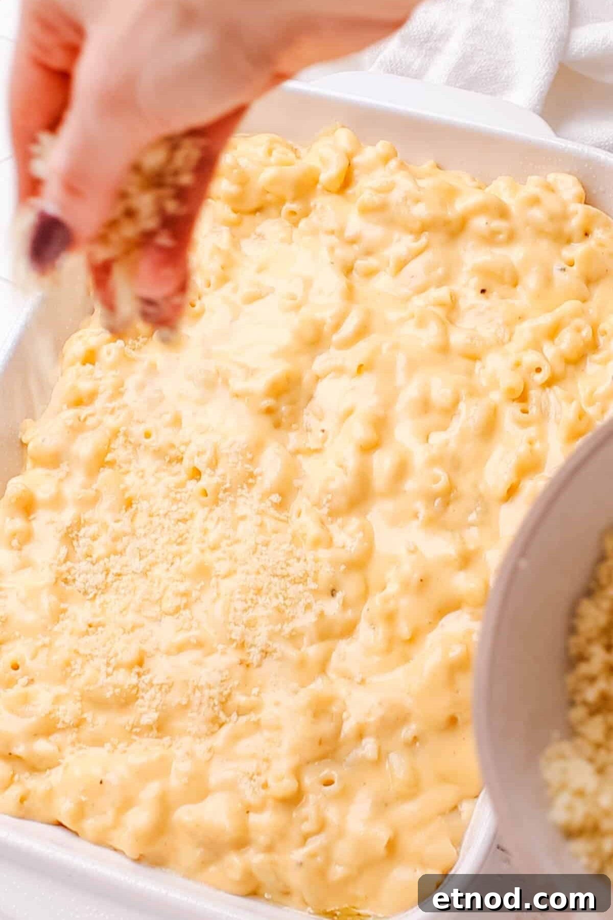 Adding bread crumbs on baked macaroni and cheese.