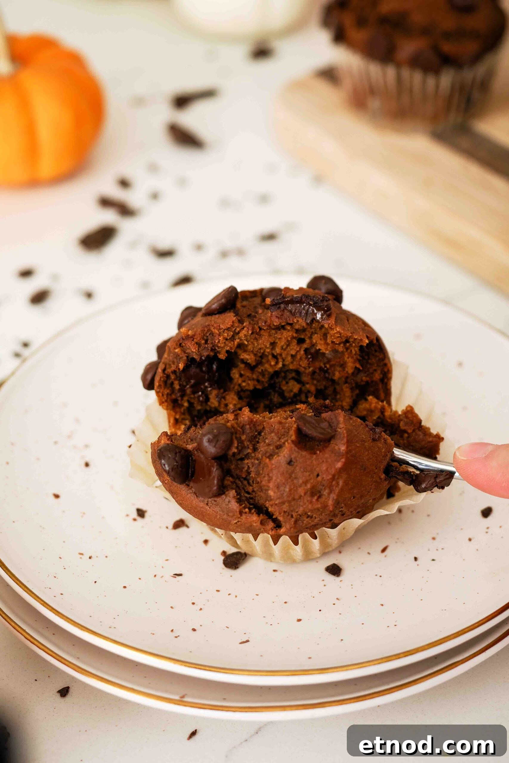 Chocolate Pumpkin Muffins with Melty Chips — Fall Baking Recipe 12 A fork divides a chocolate pumpkin muffin in two.