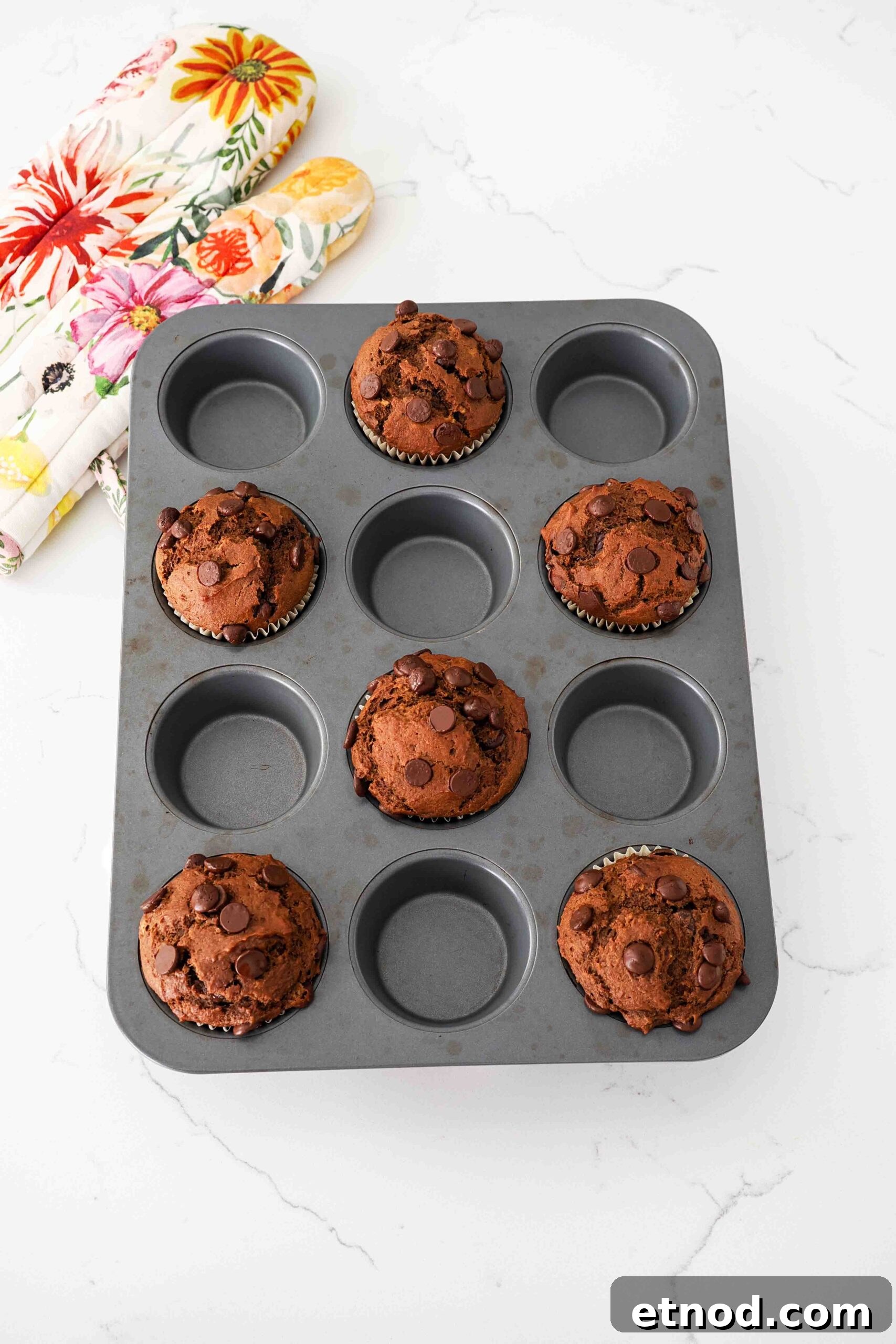 Chocolate Pumpkin Muffins with Melty Chips — Fall Baking Recipe 10 Fully baked large chocolate pumpkin muffins in a dark muffin pan.
