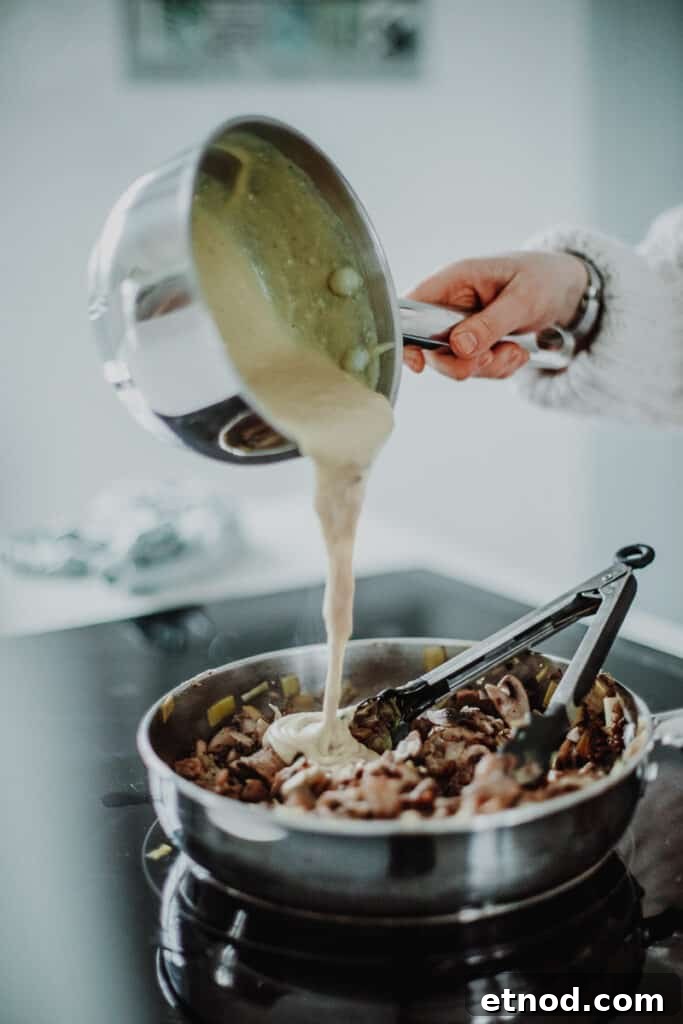 Creamy Leek and Mushroom Pie Recipe for Cozy Dinners 6 pouring the white sauce into the mushroom and leek mixture