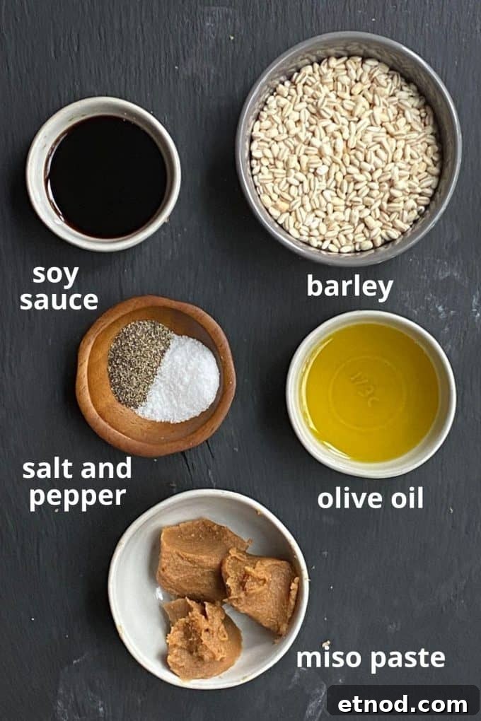 An overhead view of mushroom barley soup ingredients; soy sauce, barley, salt and pepper, olive oil, and miso paste