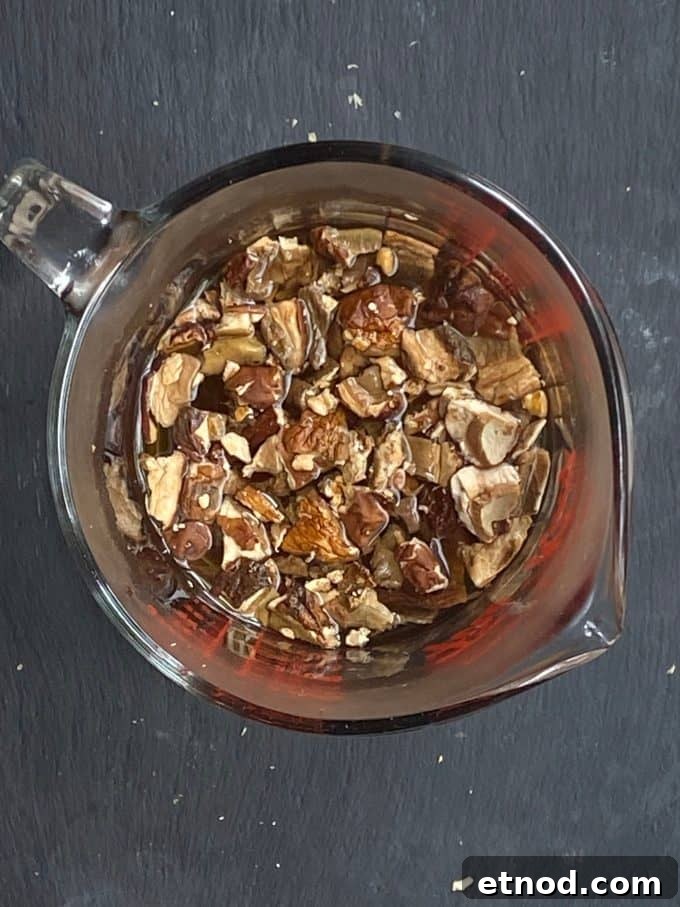 An overhead view of broken up mushroom soaking in boiling water in a measuring cup