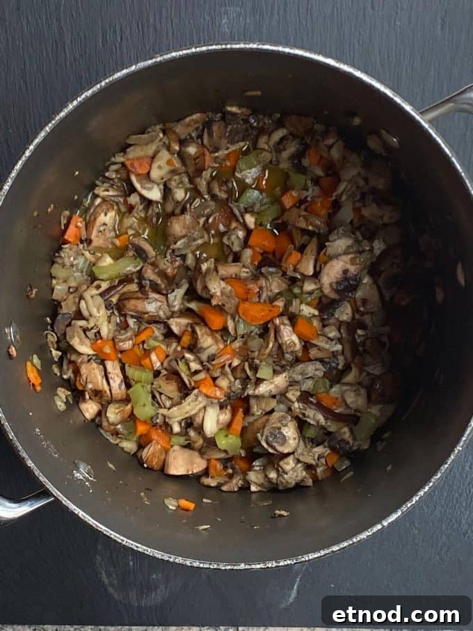 An overhead view of diced vegetables and mushrooms in a pot