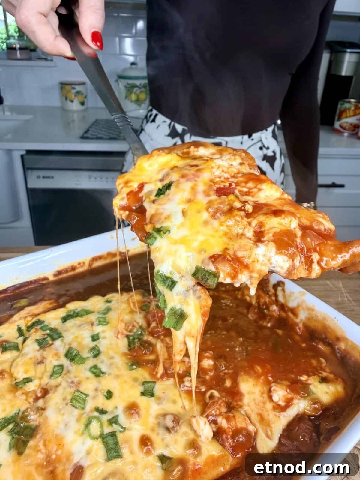 Creamy Baked Salsa Chicken Recipe for Weeknight Dinners 2 A person lifts a serving of cheesy baked lasagna from a casserole dish with melted cheese stretching, in a kitchen setting.