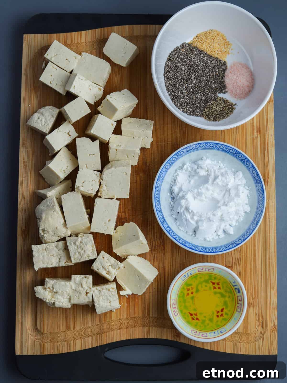 Crispy Air Fryer Tofu Coated with Chia Seeds for Extra Crunch 5 image of crispy chia tofu ingredients showing chopping board with cubes of raw tofu and three bowls showing the ingredients.