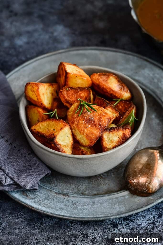 Crispy Roast Potatoes Cooked in Goose Fat 3 Bowl of crunchy roast potatoes garnished with rosemary