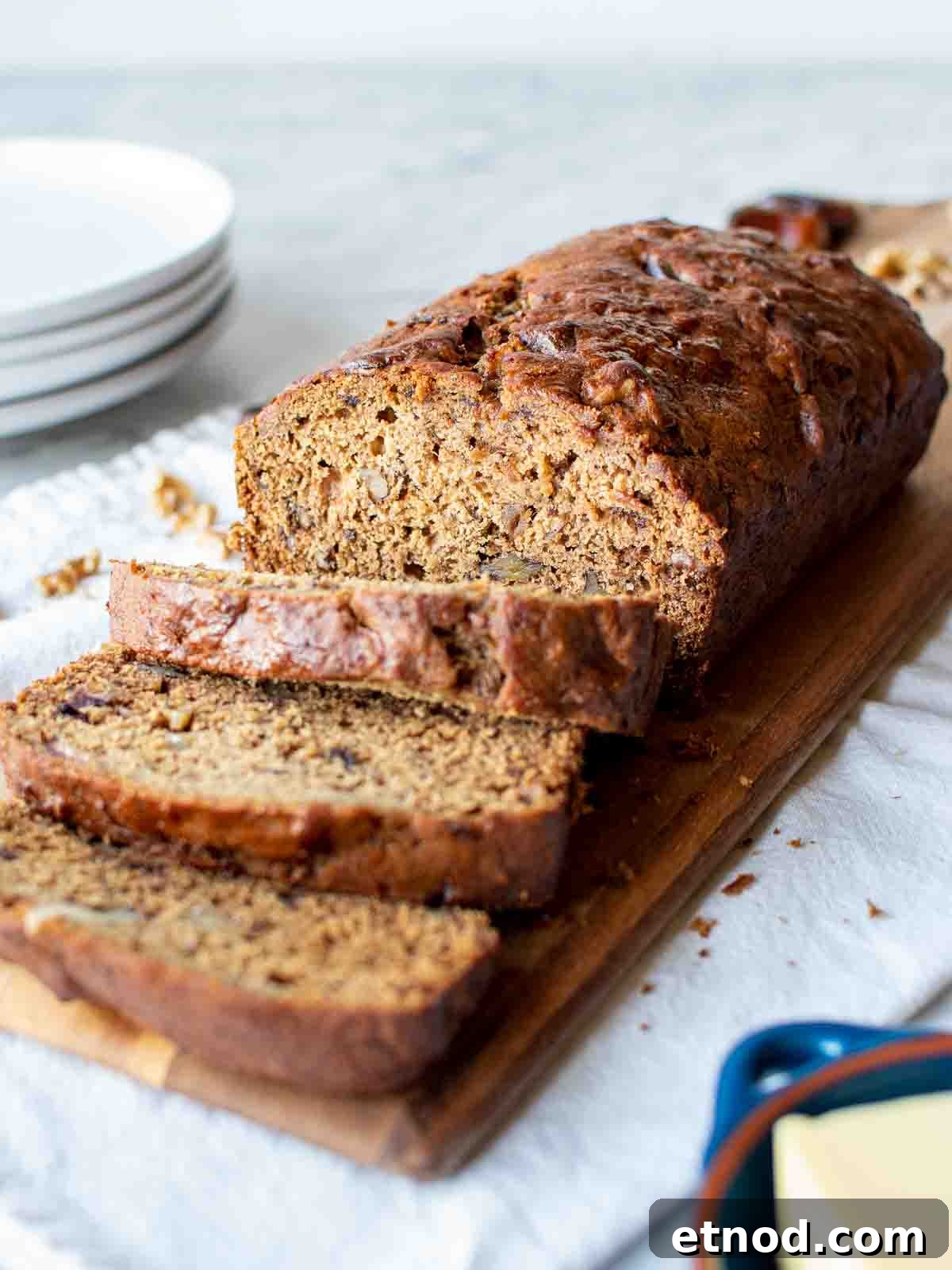Moist Date and Walnut Bread Recipe for Homemade Comfort 2 Date bread on wooden board with three slices cut.