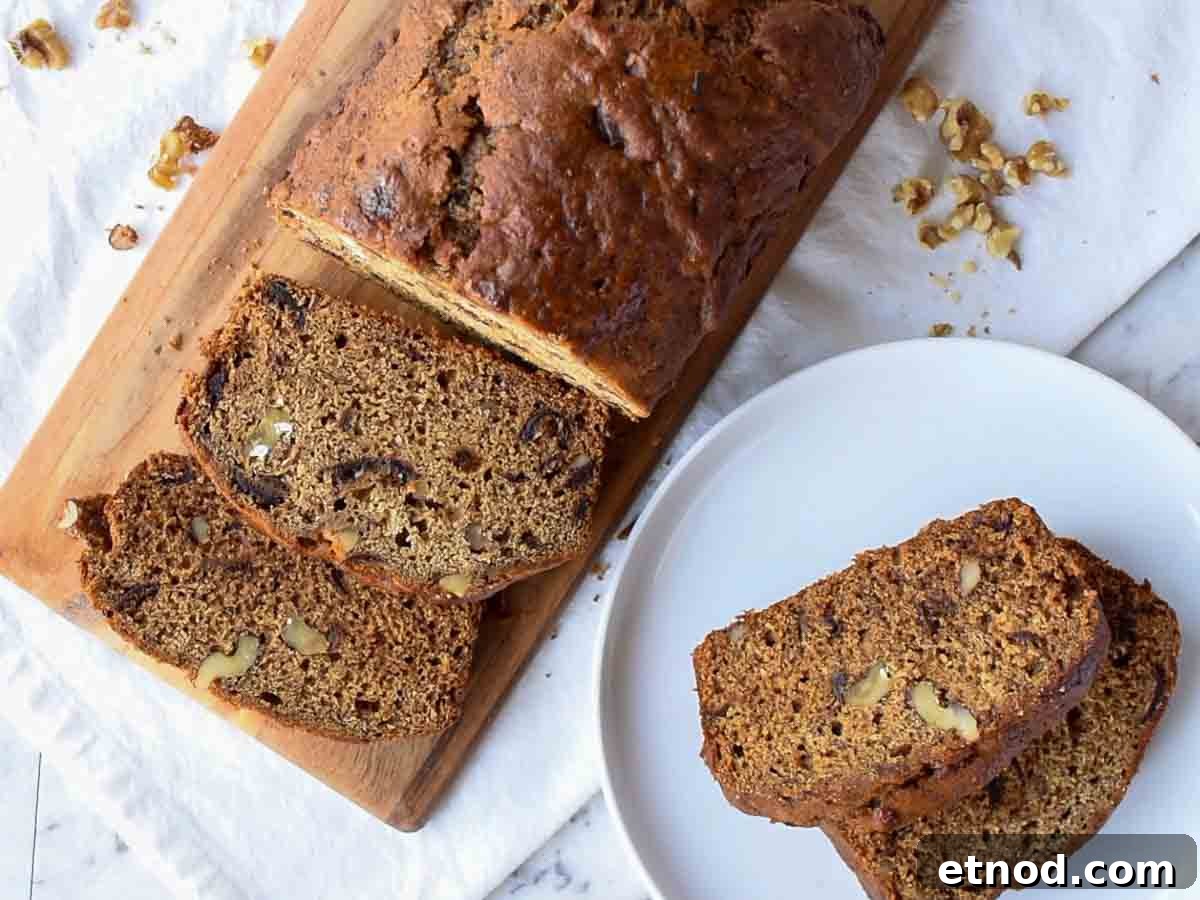Moist Date and Walnut Bread Recipe for Homemade Comfort 5 The finished bread on a wooden board with slices cut off and served on a white plate