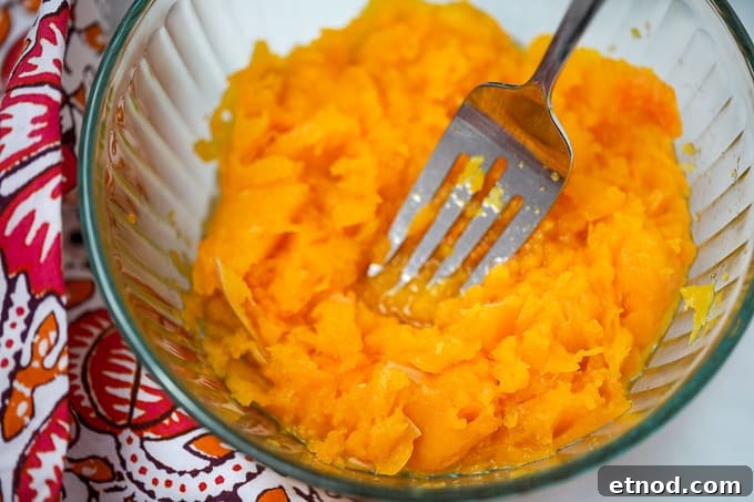 Instant Pot Butternut Squash: Tender, Creamy Side Dish 2 Butternut Squash being mashed with a fork in a glass bowl.