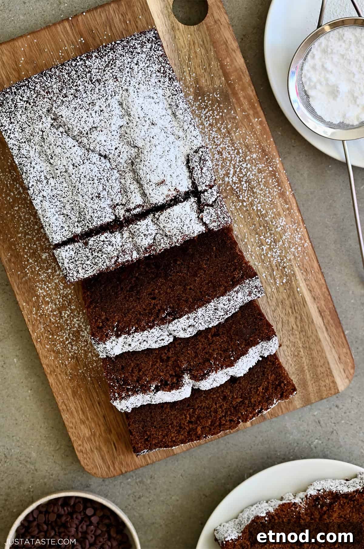 Decadent Chocolate Loaf Cake Recipe for Moist, Rich Results 2 A 9-inch chocolate loaf cake dusted with powdered sugar, with a cracked, rustic top and mini chocolate chips peeking through the crumb.
