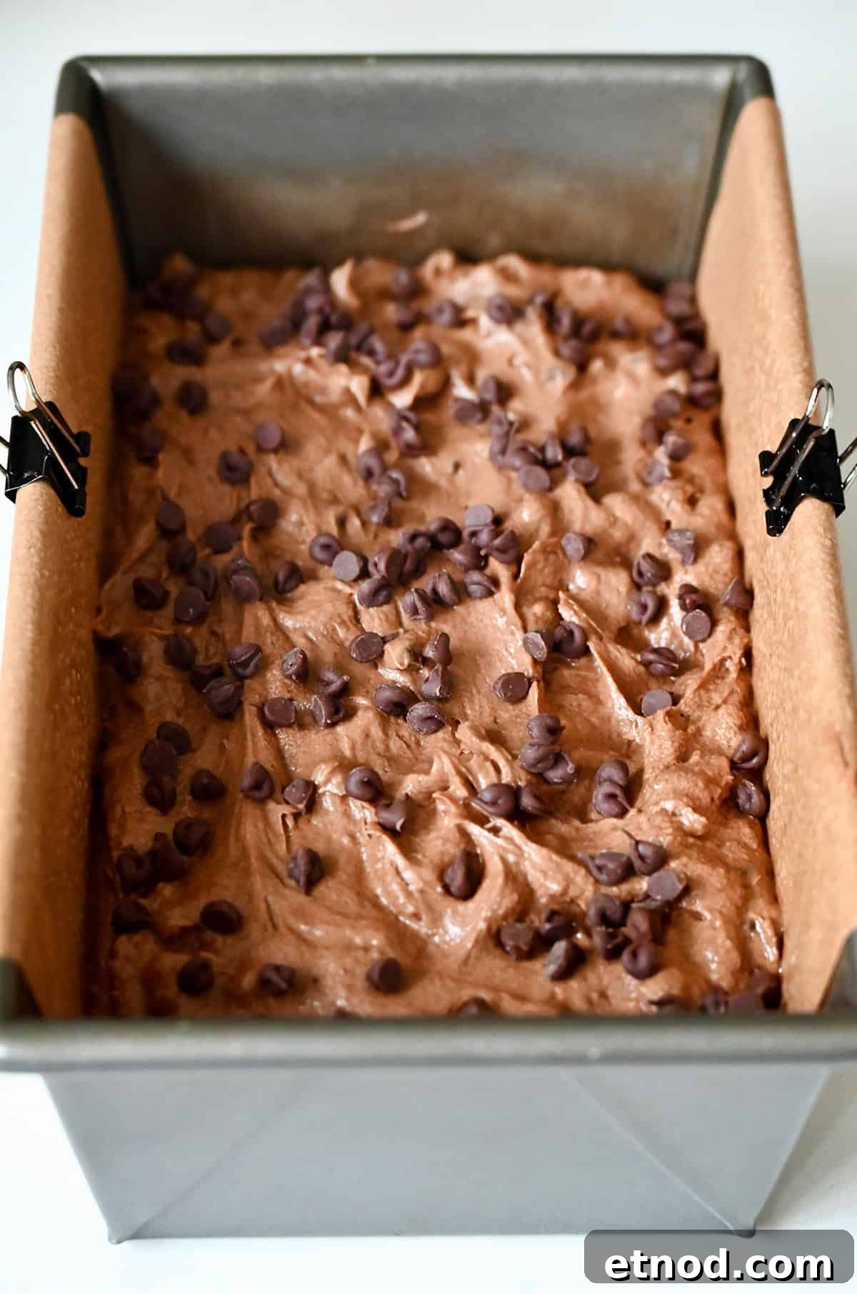 Decadent Chocolate Loaf Cake Recipe for Moist, Rich Results 9 Unbaked chocolate cake topped with mini chocolate chips in a parchment paper-lined 9x5 loaf pan.