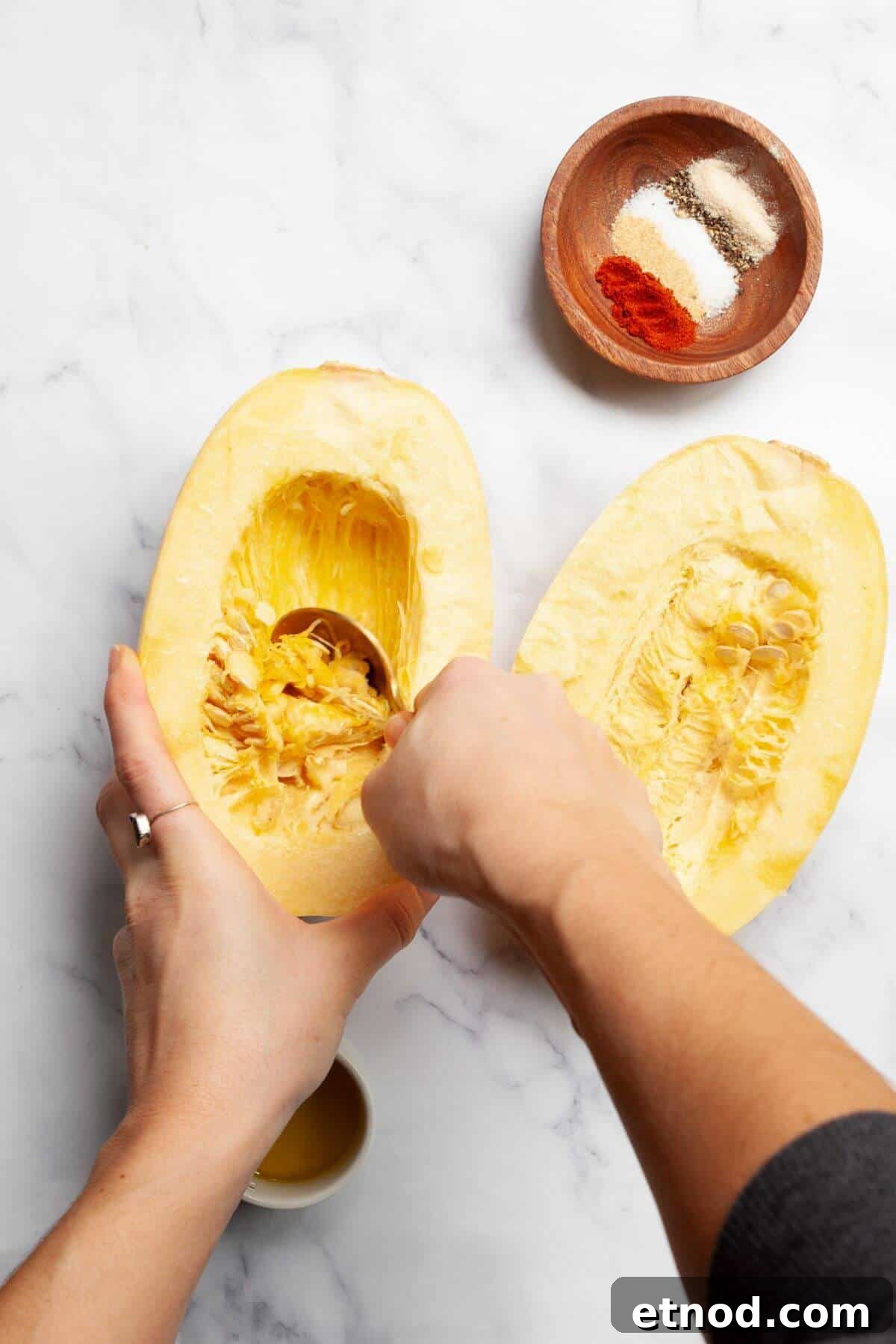 Crispy Air-Fried Spaghetti Squash Recipe 4 Scooping seeds out of raw spaghetti squash half with a spoon.