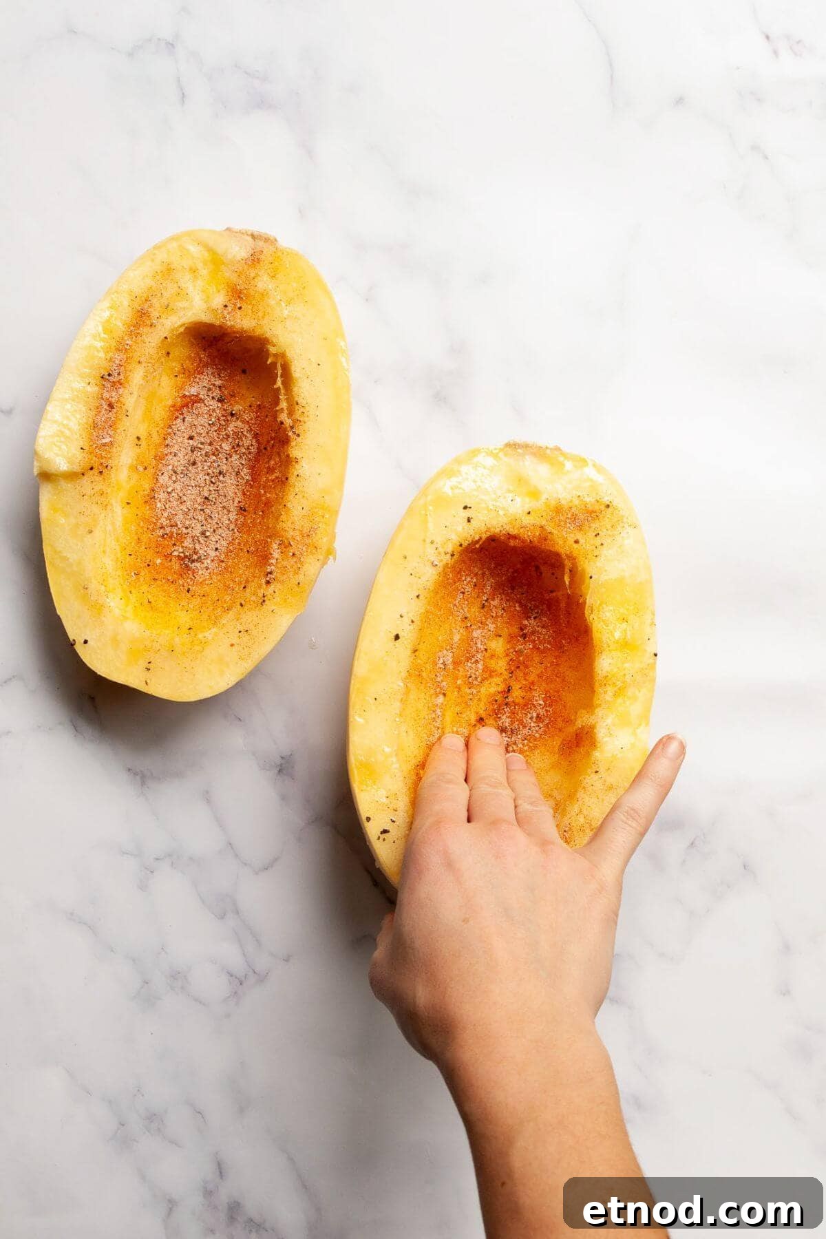 Crispy Air-Fried Spaghetti Squash Recipe 5 Seasoning spaghetti squash halves with olive oil, salt, pepper, paprika, onion powder, and garlic powder before cooking in the air fryer.