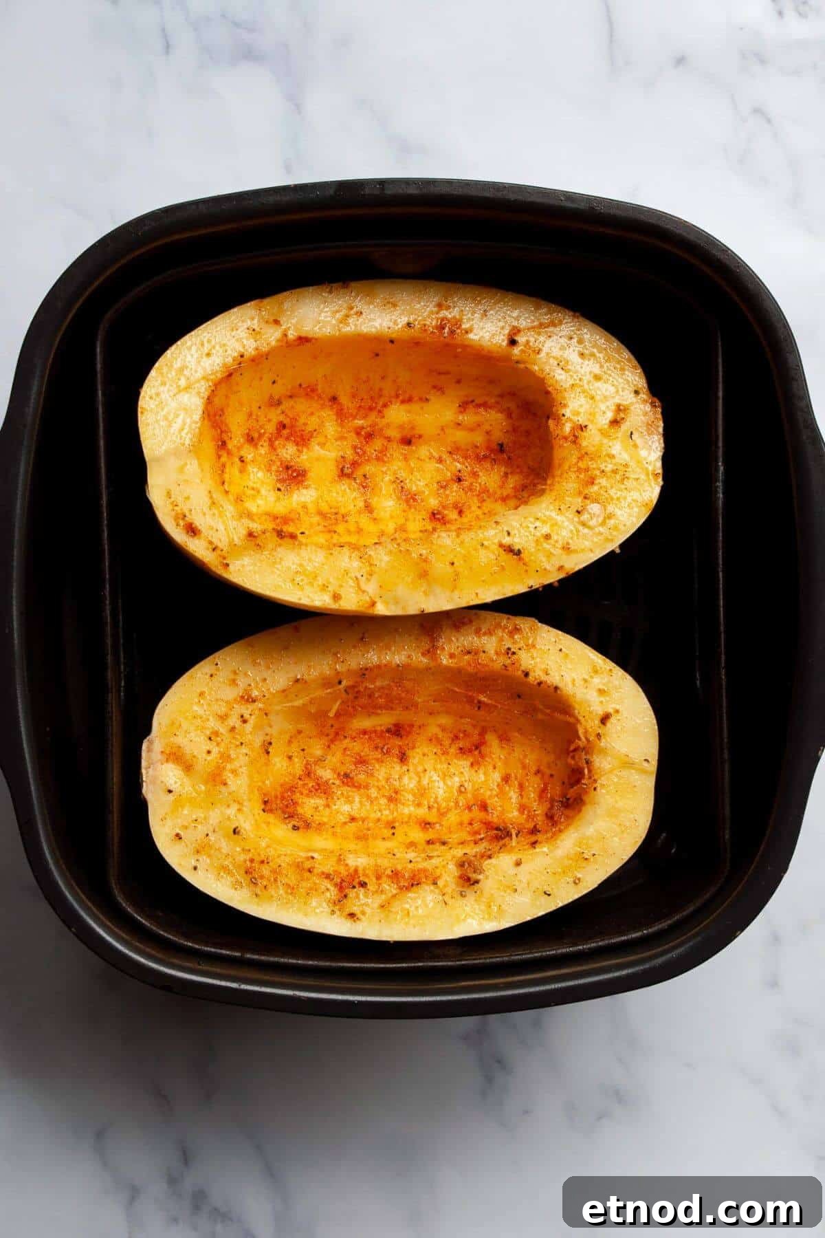 Crispy Air-Fried Spaghetti Squash Recipe 6 Seasoned spaghetti squash halves ready to cook in the air fryer basket.